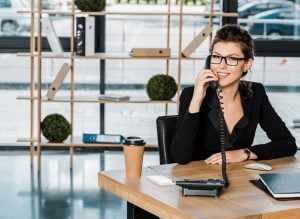 Woman happy to answer telephone at her desk, clearinghouse services, FMSCA drug testing